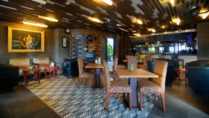 A restaurant with a bar area, wooden ceiling, patterned floor, and seating arrangements. - The Lerina Hotel Nusa Dua (Nusa Dua)
