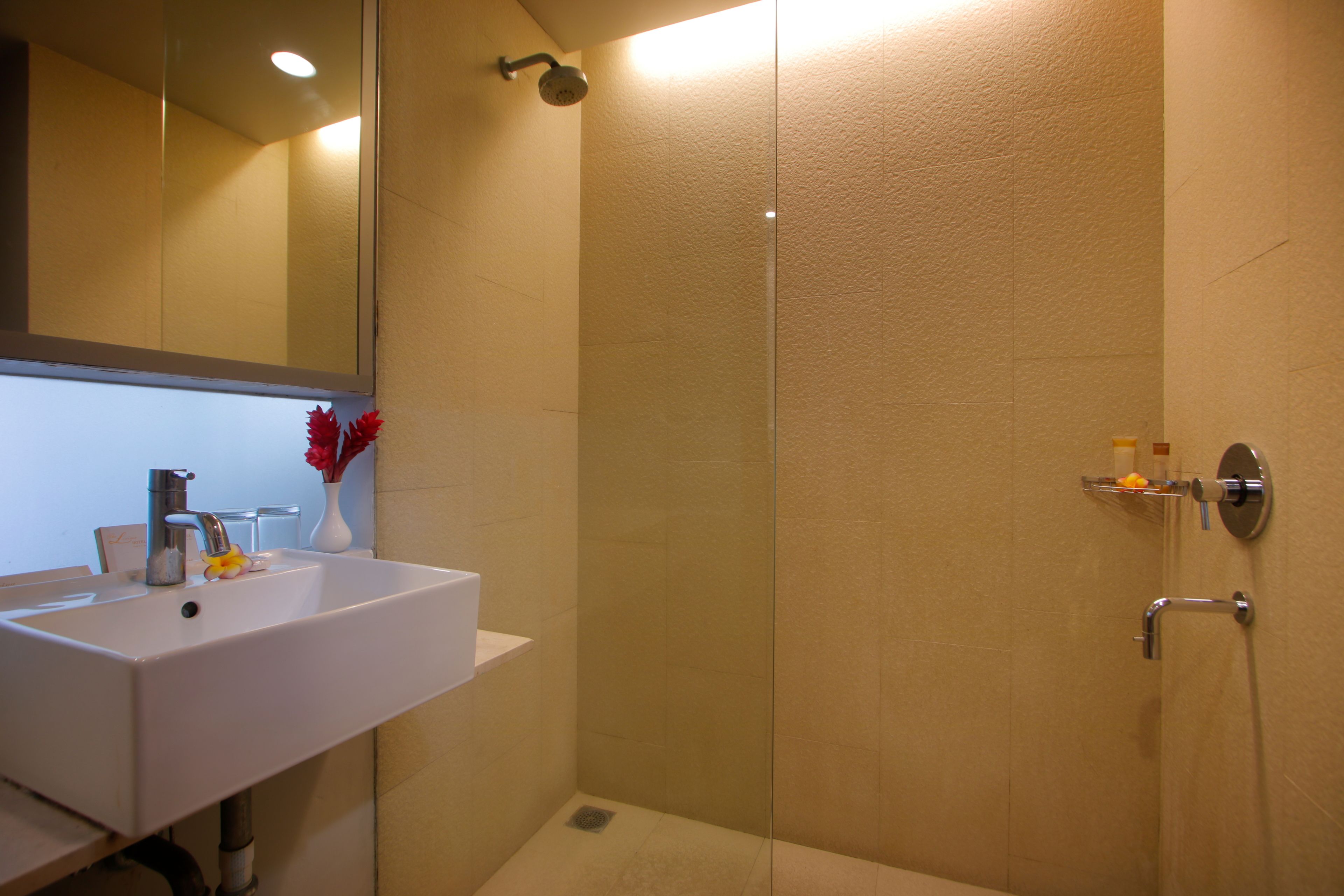 A bathroom with a white sink, a mirror, and a shower area.
