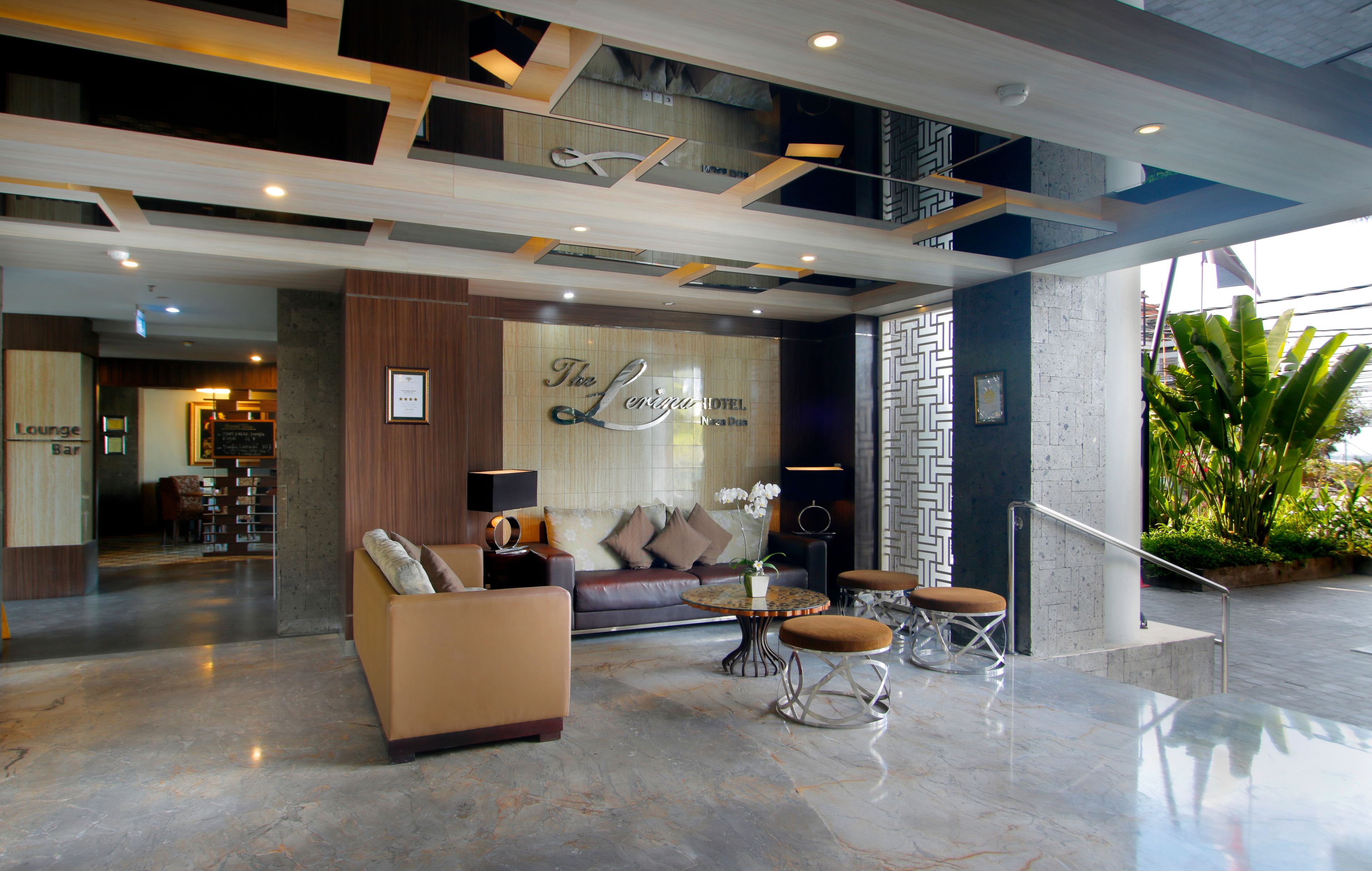 Vestíbulo de hotel con sofá, sillones, una mesa de centro y una zona de bar lounge.