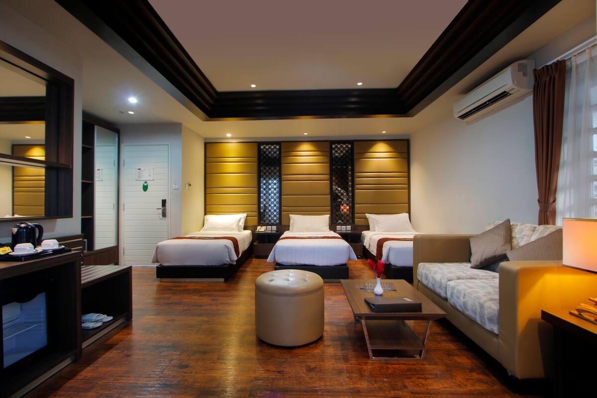 Una habitación de hotel con tres camas, un sofá, una mesa de centro y un espejo.