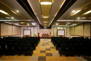 A conference room with rows of chairs, a podium, and a projection screen.