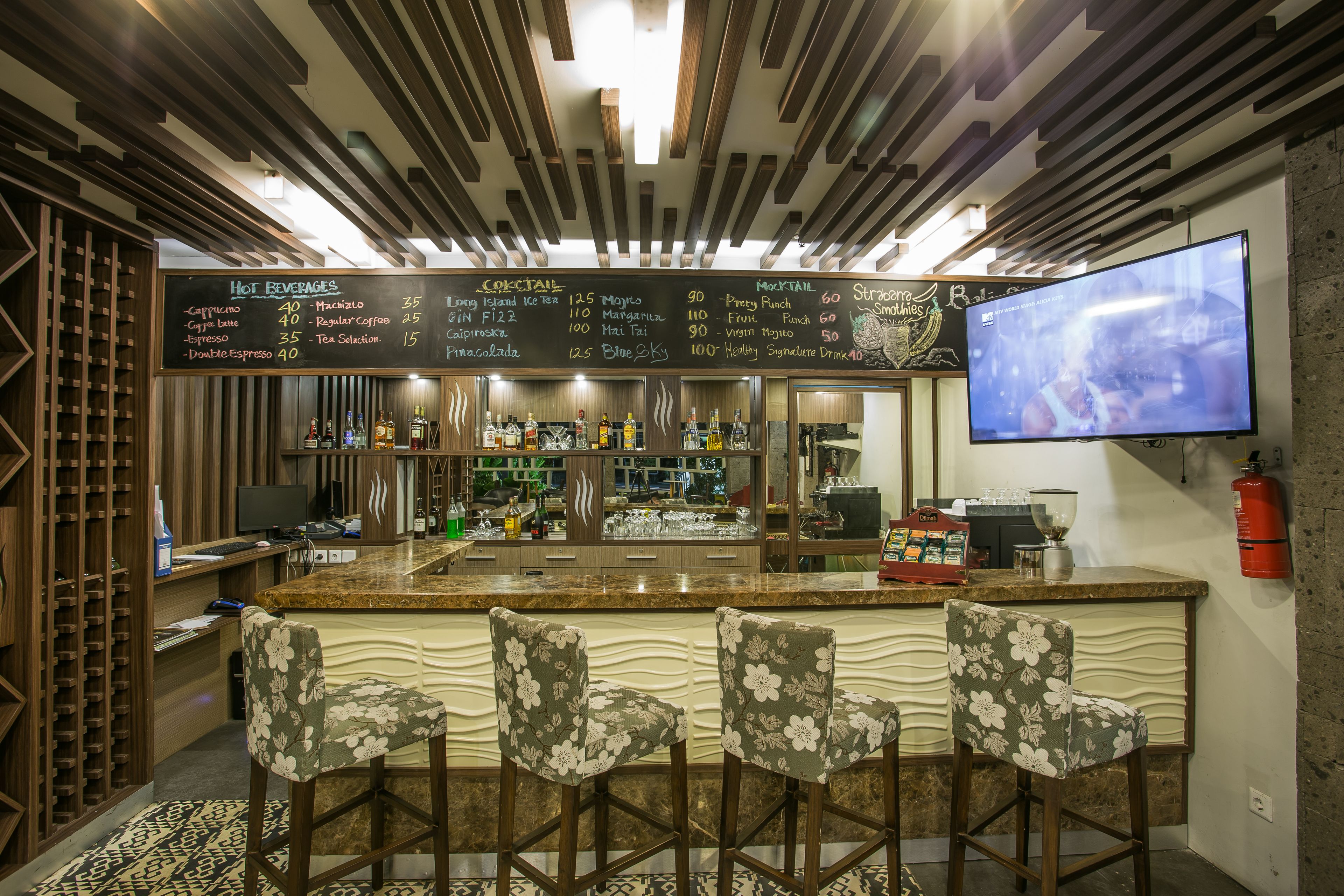 Angolo bar con lavagna dei menu, sgabelli da bar, televisore e refrigeratore per vino.
