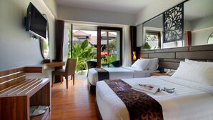 A hotel room with two beds, a desk, a TV, and a balcony with a view of the outside. - The Lerina Hotel Nusa Dua (Nusa Dua)