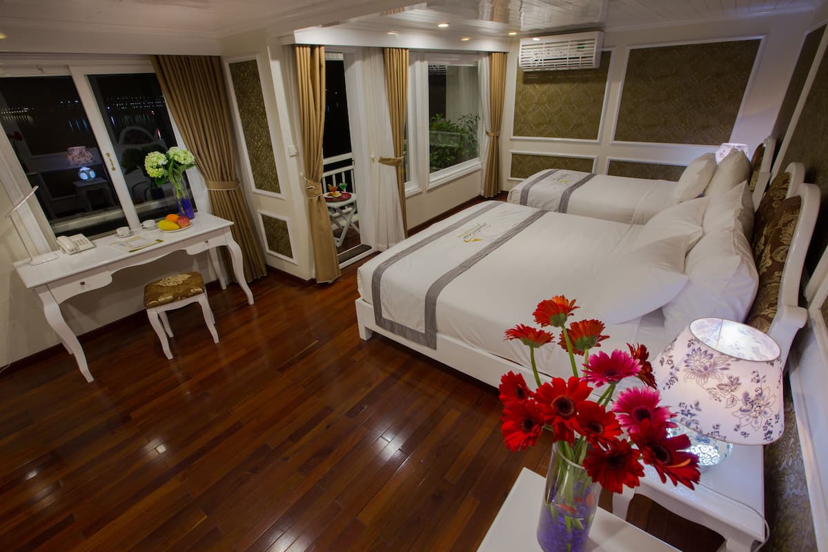 A hotel room with a large bed, a desk, and a window with curtains.