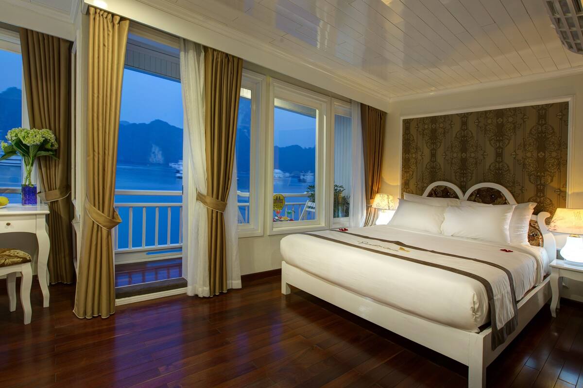 A bedroom with a large bed, a desk, and a view of the sea.