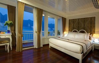 Un dormitorio con una cama grande, un escritorio y vista al mar.