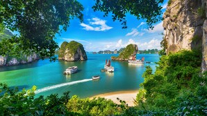 A coastal scene with boats, clear water, and lush greenery. - Signature Royal Halong Cruise (Hong Gai)