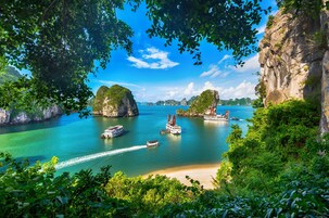 Paisaje costero con barcos, agua cristalina y vegetación exuberante.