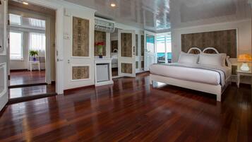 A spacious bedroom with a large bed, wooden flooring, and a view of the outdoors.