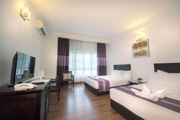 A hotel room with two beds, a desk with a phone, a chair, and a large window with curtains.