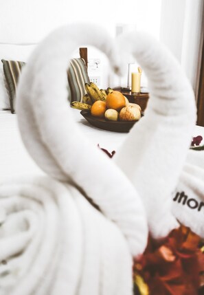 A bed with a white blanket and a heart-shaped pillow.