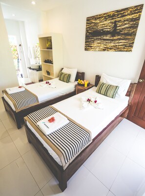 A hotel room with two beds, a bathroom, and a painting of a sunset over water.
