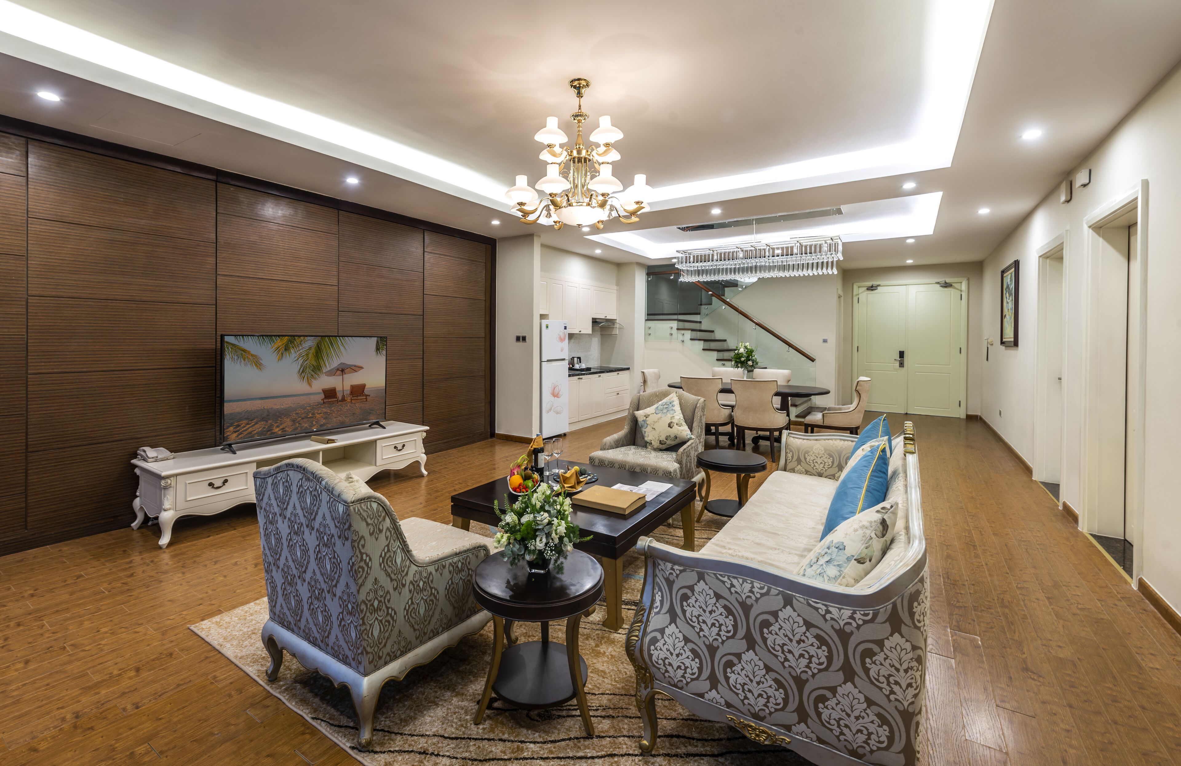 A modern living room with a TV, sofas, a coffee table, and a chandelier.