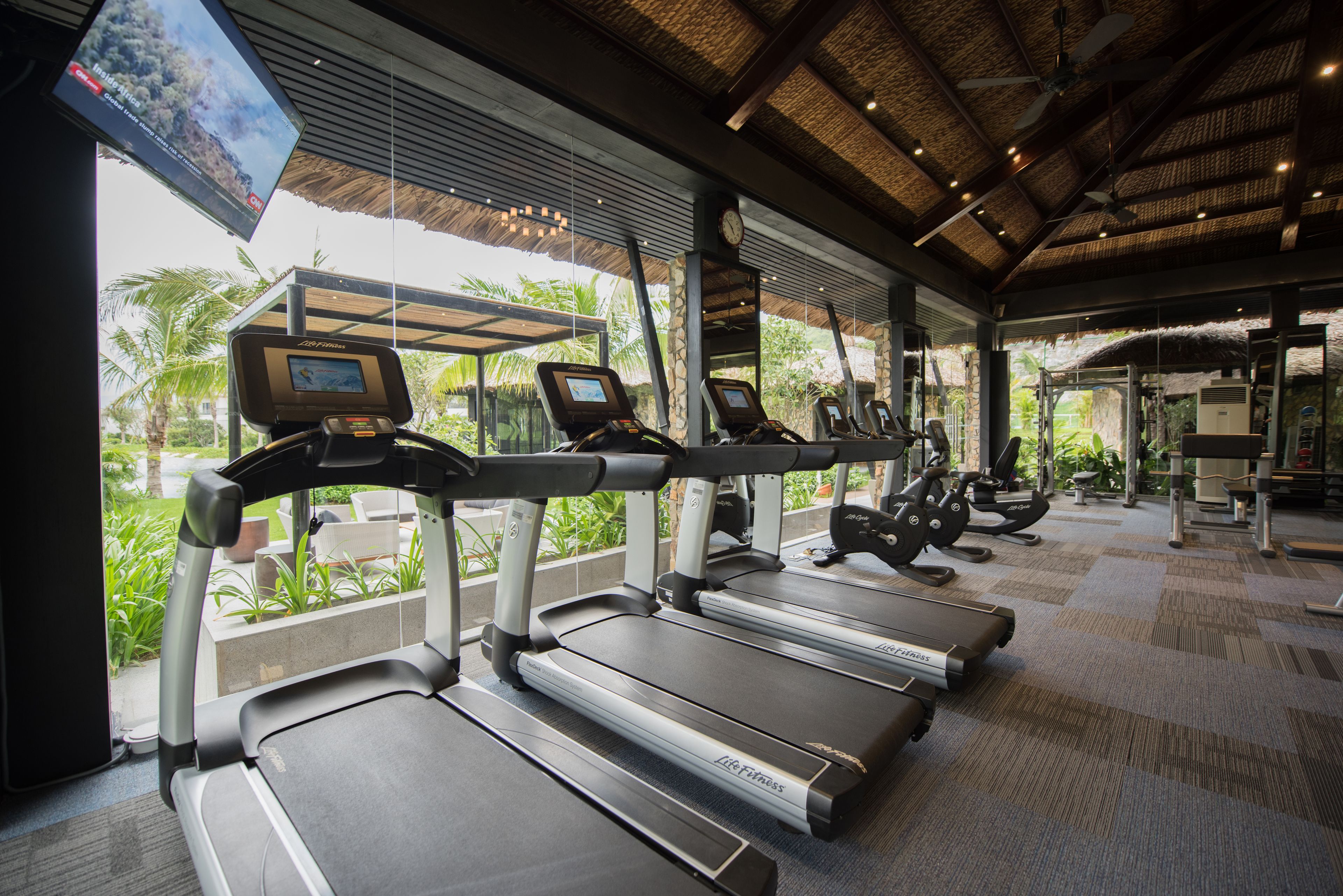 A gym with treadmills, exercise equipment, and a TV screen.