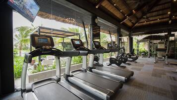 A gym with treadmills, exercise equipment, and a TV screen.
