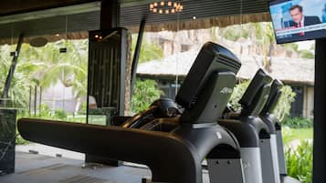 A treadmill in a hotel lobby with a view of a tropical outdoor area.