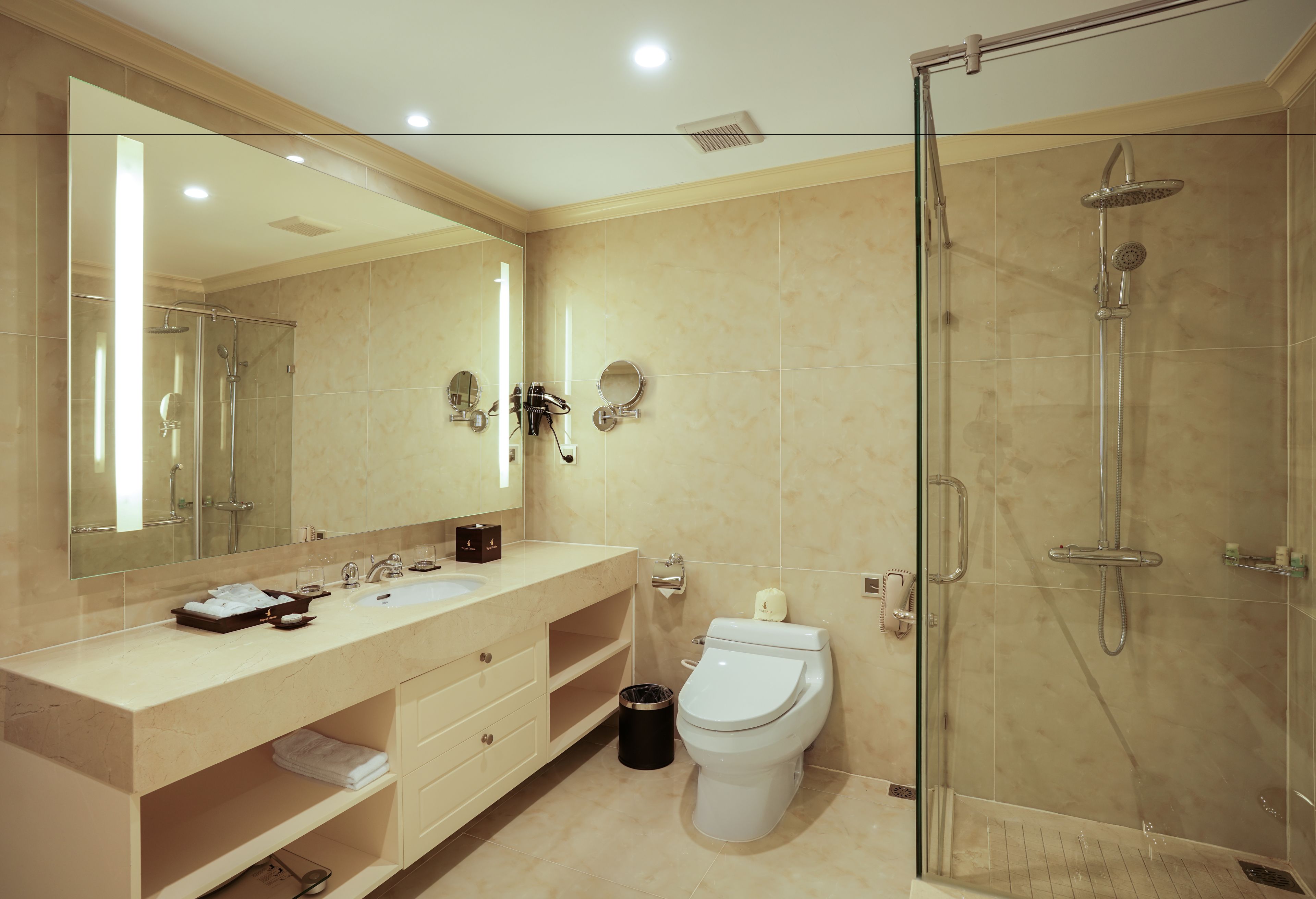 Une salle de bain moderne avec un grand miroir, un lavabo, des toilettes et une douche à parois de verre.