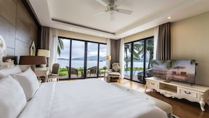 Un dormitorio amplio con una cama grande, televisión y vista al océano.