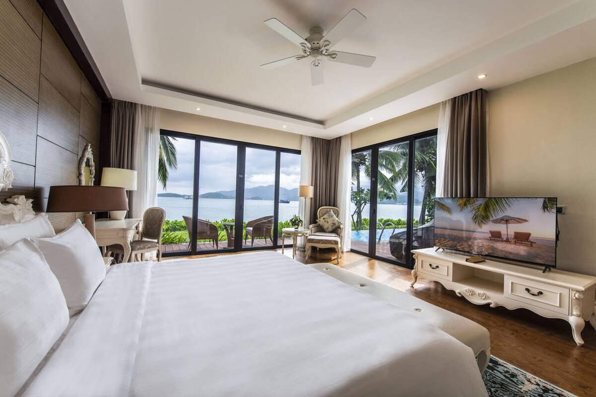 A spacious bedroom with a large bed, a television, and a view of the ocean.