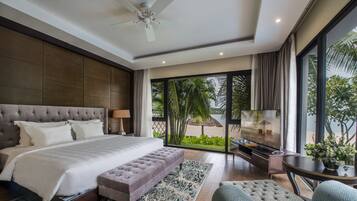 A spacious bedroom with a large bed, a seating area, and a TV.