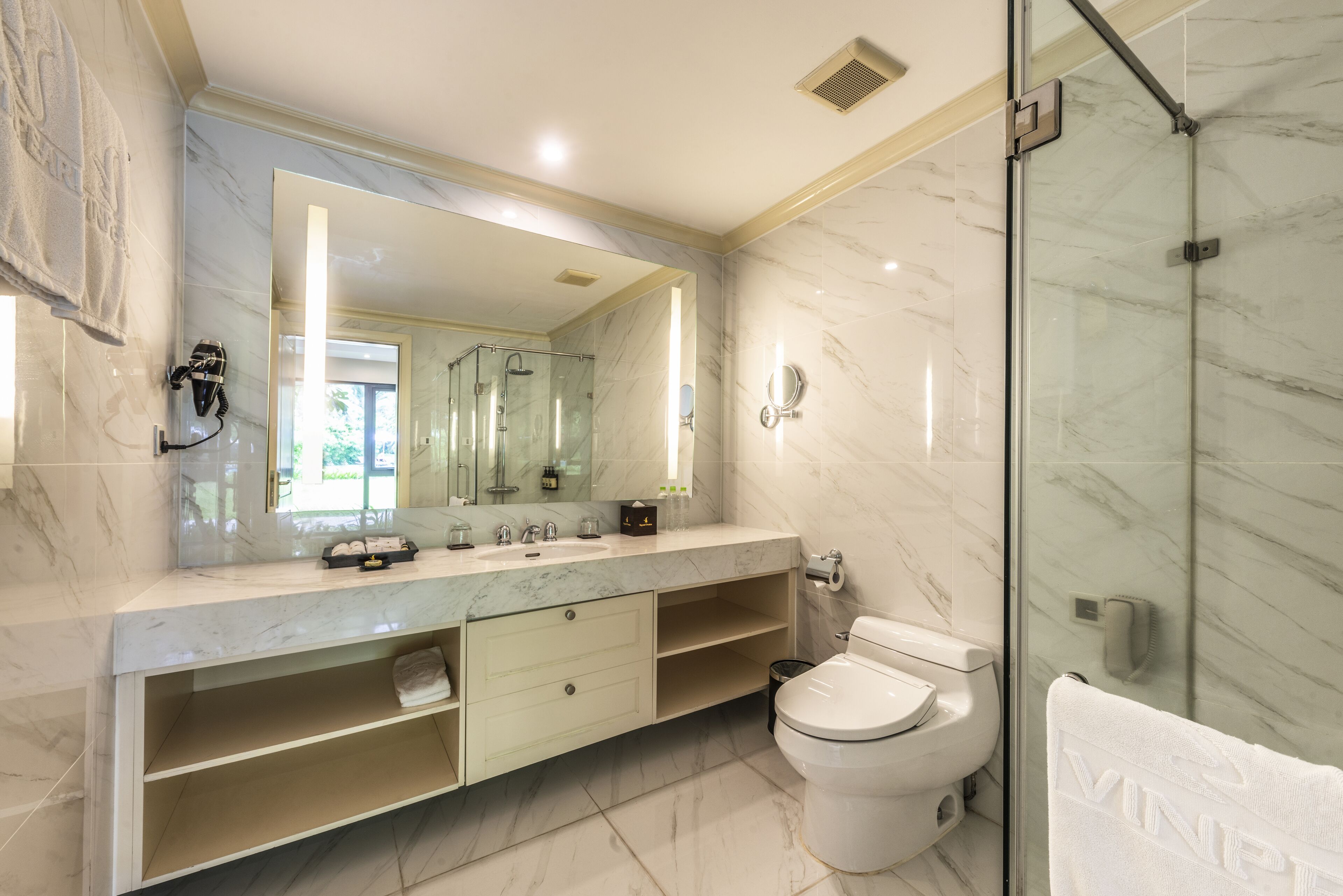 Une salle de bain moderne avec un grand miroir, une douche en verre et un comptoir en marbre.