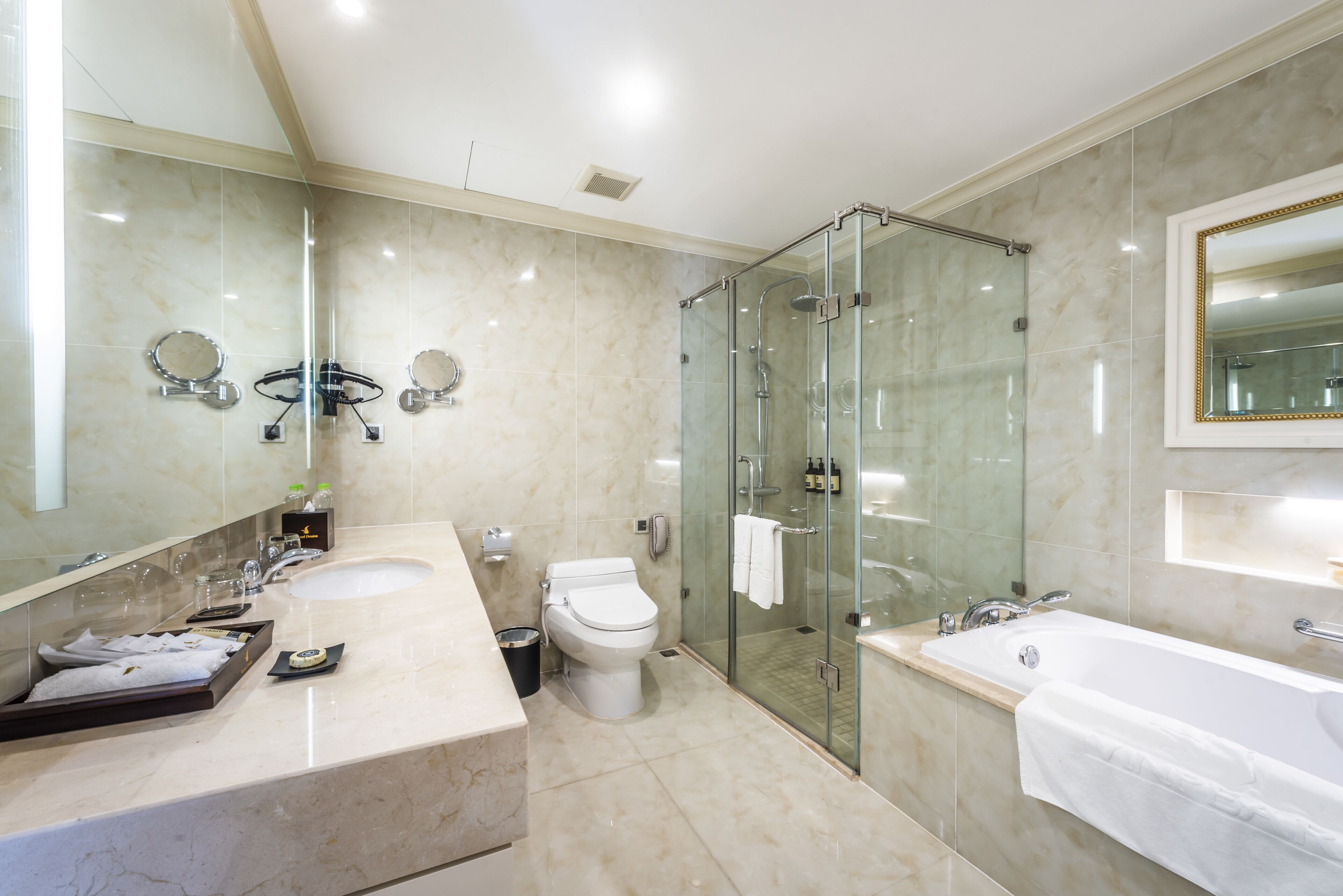 A modern bathroom with a glass-enclosed shower, a large mirror, and a bathtub.