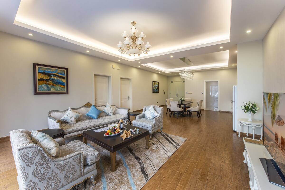 A spacious living room with a sofa set, a coffee table, and a chandelier.