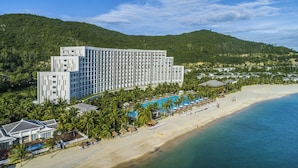 Un resort con un gran edificio de hotel, piscina y playa.