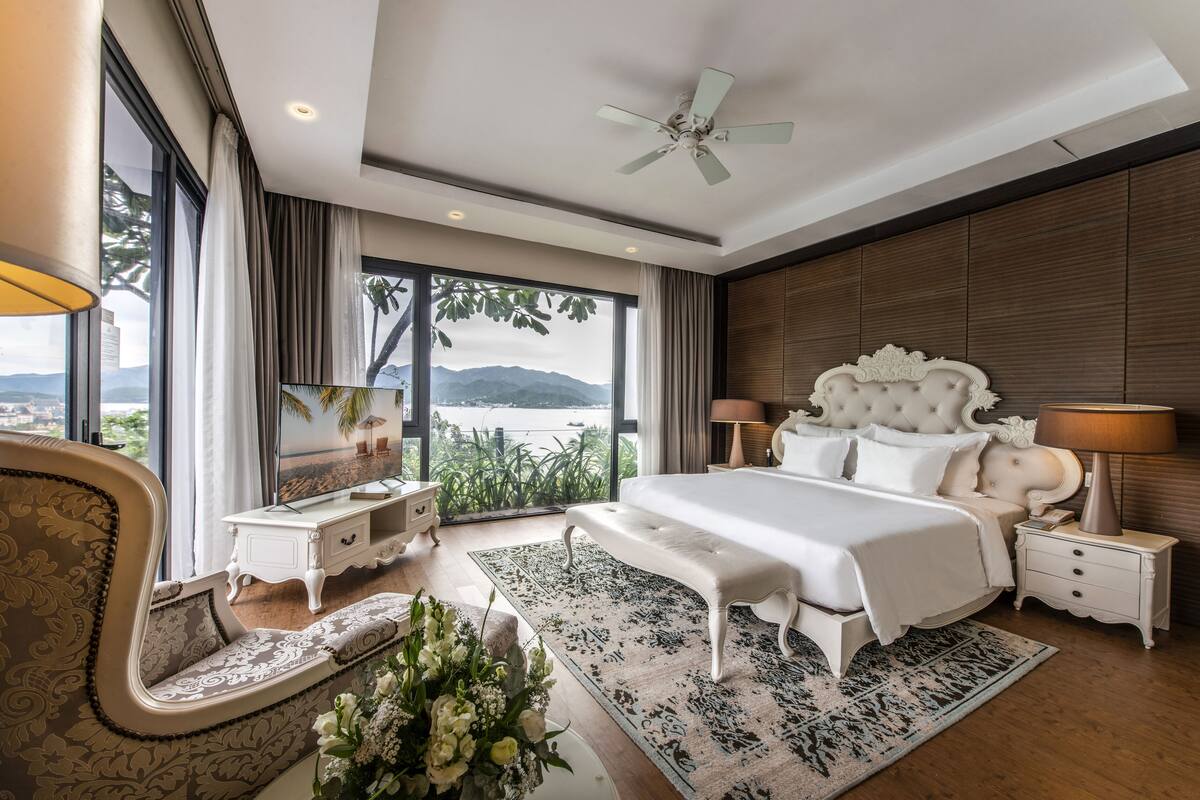 A spacious bedroom with a large bed, a ceiling fan, and a view of the mountains through large windows.