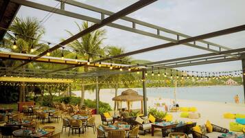 Enjoy meals with a view of the sea from our outdoor dining area, featuring a thatched-roof gazebo and comfortable seating options.