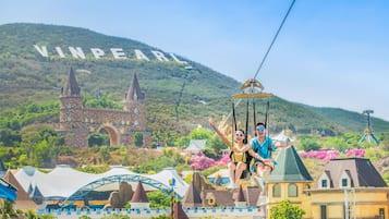 A theme park with a castle, a roller coaster, and a cable car ride.