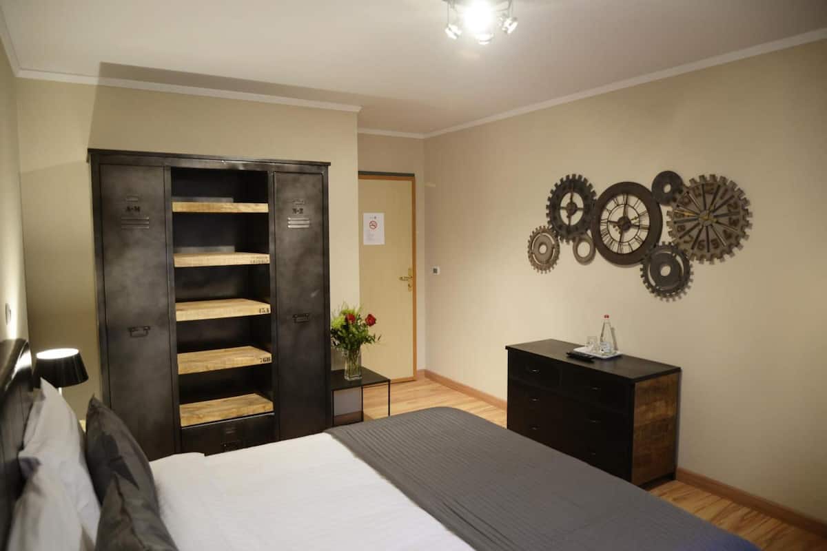 Quarto com cama, guarda-roupa, penteadeira e uma decoração de engrenagens na parede.