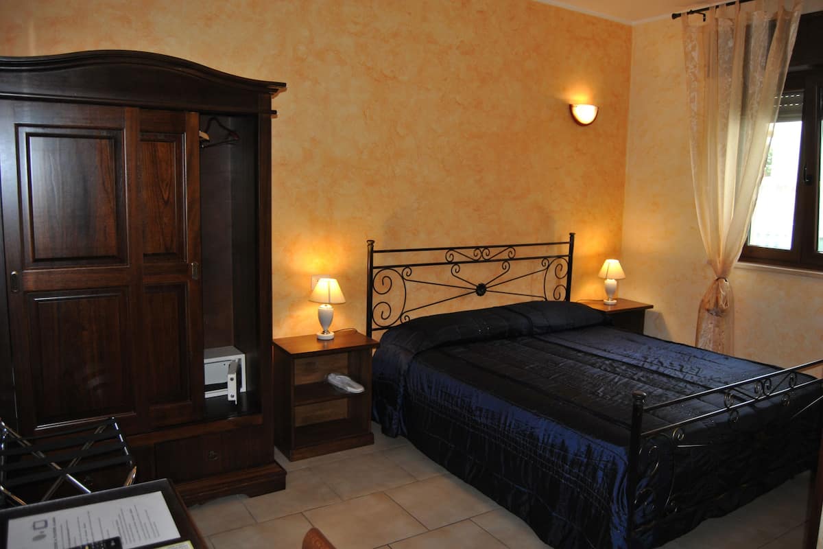 Une chambre à coucher avec un lit, des tables de chevet, une armoire et une fenêtre avec des rideaux.