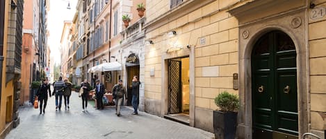 A cobblestone street lined with historic buildings, including a building with a green door and the number 24.