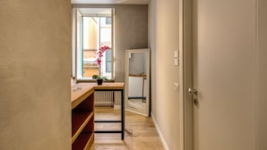 A hallway with a wooden table, a potted plant, and a radiator. - The Spanish Suite Piazza di Spagna (Rome)