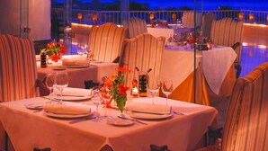 A restaurant with tables set for dining, large windows, and a view of the night sky. - Royal Monte Carlo Sharm El Sheikh - Adults only (Sharm El Sheikh)