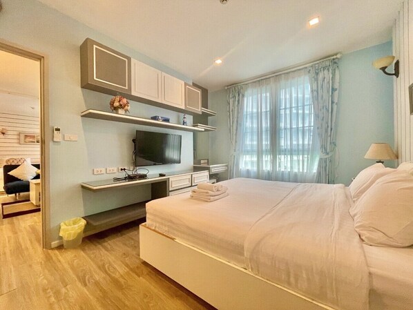 A bedroom with a bed, a desk, and a television.