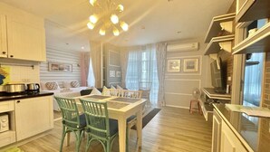 A modern kitchen with white cabinets, a dining table with chairs, and a chandelier. - Summer Huahin Condo 2 Bedrooms Pool View By Dome (Hua Hin)