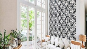 A bright living room with a white sofa, a patterned wall, and a wooden floor. - Summer Huahin Condo 2 Bedrooms Pool View By Dome (Hua Hin)