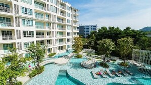 A multi-story hotel with a rooftop pool area featuring a water slide, lounge chairs, and landscaped greenery. - Summer Huahin Condo 2 Bedrooms Pool View By Dome (Hua Hin)