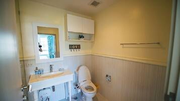 A bathroom with a toilet, sink, mirror, and a shelf with a 'LOVE' sign.