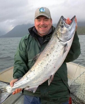 A person holding a large fish on a boat. - Silvern Lake Trail Bed & Breakfast (Smithers)