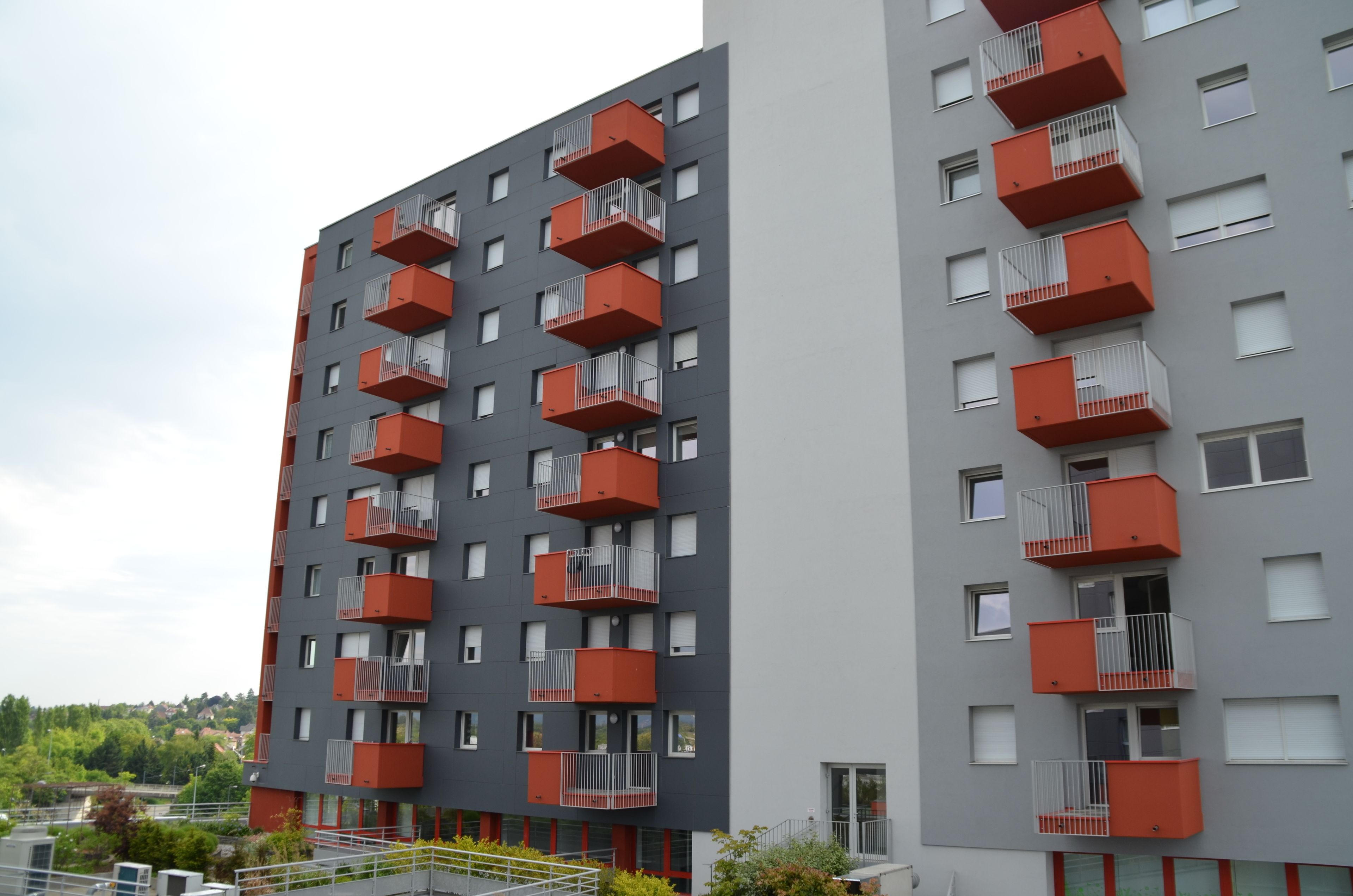 Een modern appartementencomplex met meerdere balkons en een grijze gevel.