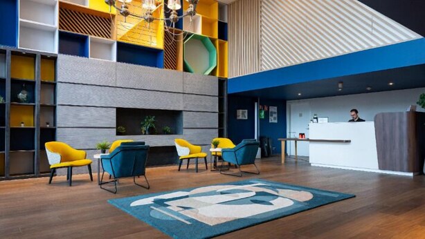 A modern lobby with a reception desk, seating area with chairs, and a fireplace. - Appart du Trident (Mulhouse)