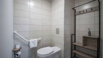 A bathroom with white tiles, a toilet, a towel rack, a shelf with a vase, and a toilet paper holder.