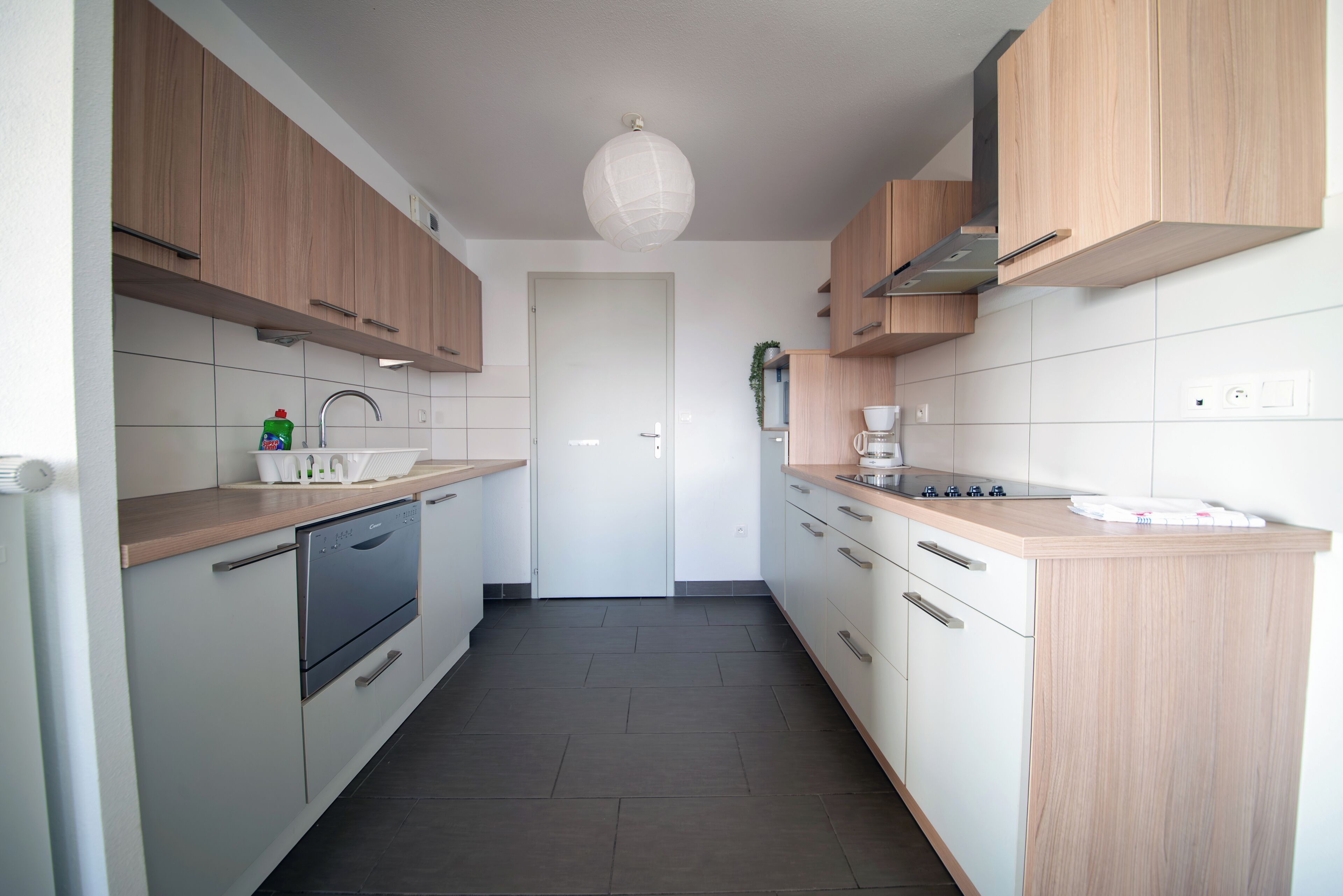 Eine moderne Küche mit Holzausstattung, einem eingebauten Backofen und einer weißen Küchenrückwand.