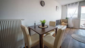 A dining area with a table, chairs, a potted plant, and a radiator.