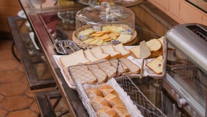 Un buffet proposant une variété de plats, notamment du pain, des pâtisseries et différents types de fromages, présentés sur des étagères en verre.