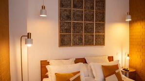 Une chambre d’hôtel avec un lit soigneusement fait, deux lampes de chevet et un panneau décoratif au mur.