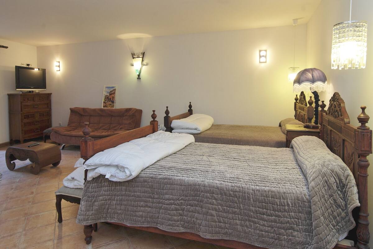 Ein Schlafzimmer mit zwei Betten, einem Fernseher, einer Holzkommode und einem Stuhl.